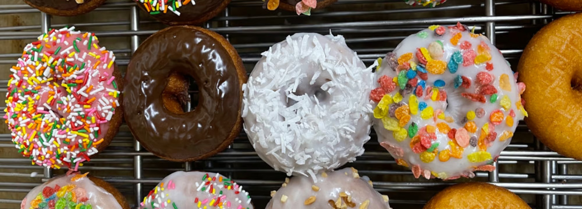 Sprinkle, chocolate, coconut and fruity-cereal donuts on a cooling rack